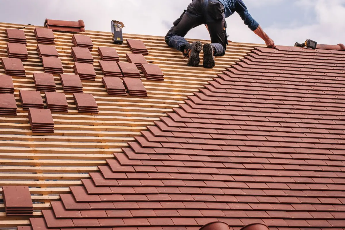 Roofing professional installing shingles on a residential roof.
